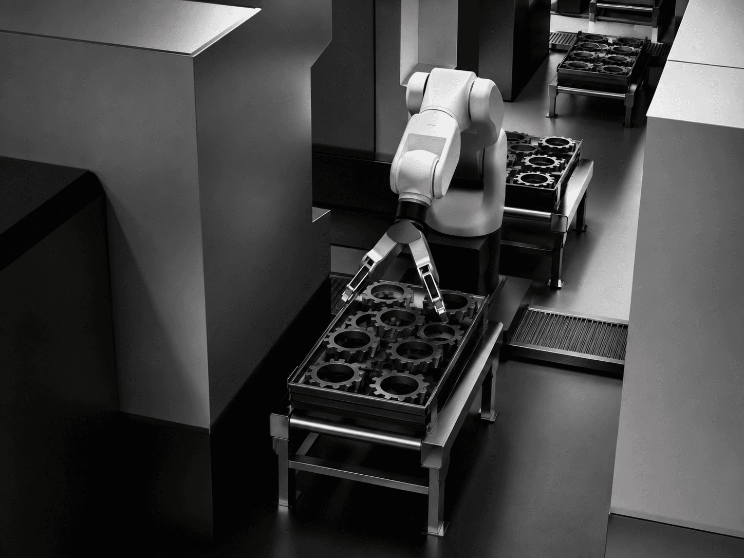 Robotic arm handling a tray of inspected gears